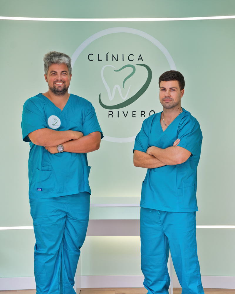 Daniel y Alejandro Rivero Sanz, con uniforme sanitario, ante el rótulo de Clínica Rivero